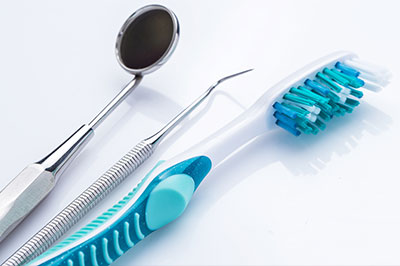 An image of a dental hygiene kit displayed on a white surface, featuring dental tools and toothbrushes.