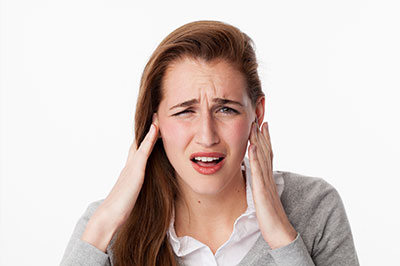 A woman with a pained facial expression, holding her head and wearing a concerned or distressed expression.