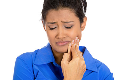 A woman with a concerned expression, holding her hand to her mouth and looking downward.