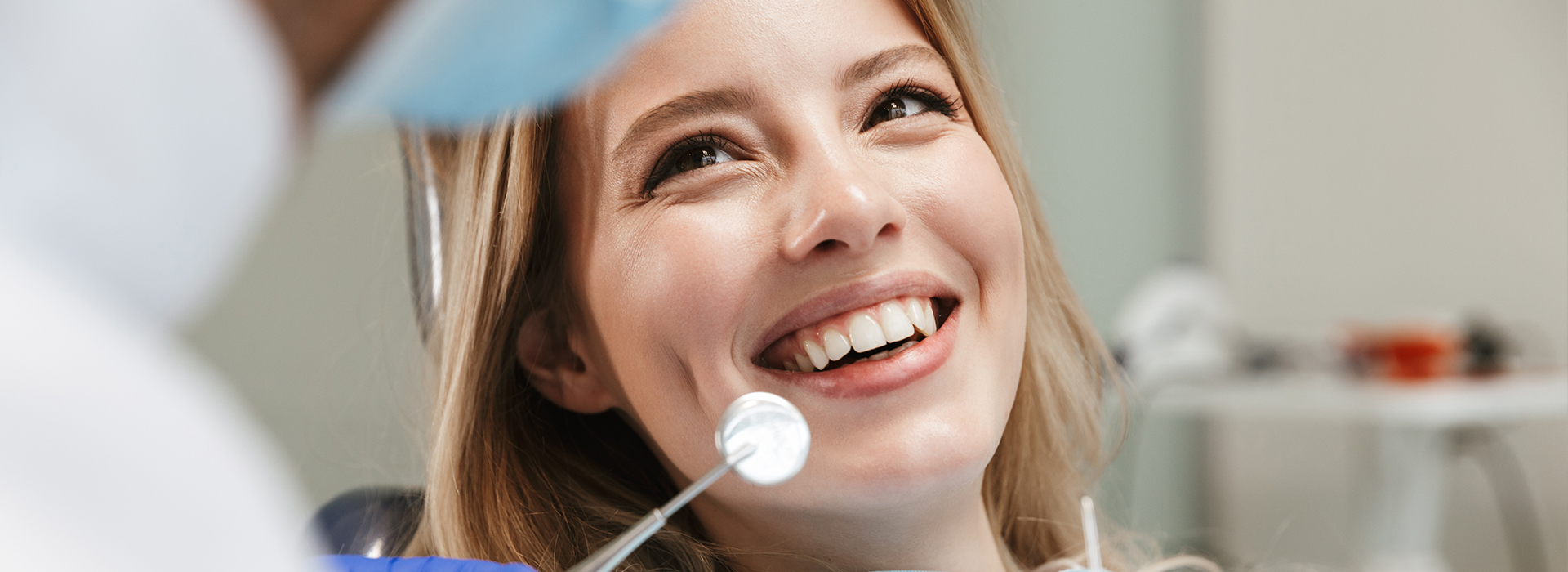 A woman in a dental chair with a smile, receiving dental care from a professional.
